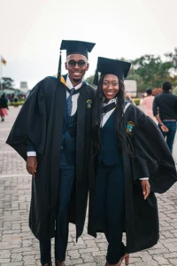 Des jeunes diplômés en toge posent ensemble, sourire aux lèvres, après leur réussite